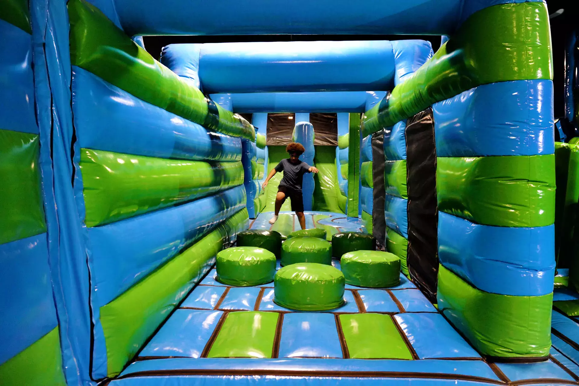 Boy running over bouncy air filled bubbles in an inflatapark.